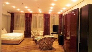 Hotelkamer met een bed, twee fauteuils, een kleine tafel, een televisie en een schuifdeurkast.