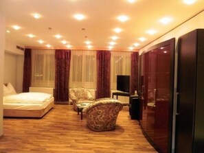 A hotel room with a bed, two armchairs, a small table, a TV, and a sliding door closet. - Stadthotel Restaurant Auerhahn (Voecklabruck)