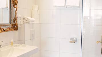 Ein Badezimmer mit weißem Waschbecken, WC und Duschbereich.