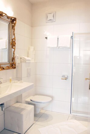 A bathroom with a white sink, toilet, and shower area. - Stadthotel Restaurant Auerhahn (Voecklabruck)