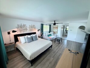A modern bedroom with a bed, bedside tables, a sofa, and a ceiling fan. - Sarasota Private Gateway Paradise (Sarasota)