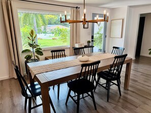 A dining area with a long wooden table, black chairs, a woven placemat, and a modern chandelier. - Sarasota Private Getaway Paradise (Sarasota)