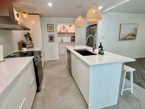 A modern kitchen with white cabinetry, a central island with a sink, and pendant lighting. - Sarasota Private Getaway Paradise (Sarasota)