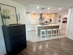 A modern kitchen with a central island, white bar stools, and pendant lighting. - Sarasota Private Getaway Paradise (Sarasota)