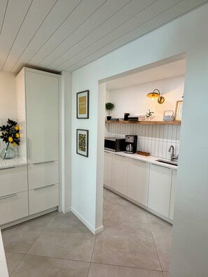 A modern kitchen with white cabinetry, a built-in microwave, and a countertop with a coffee maker. - Sarasota Private Gateway Paradise (Sarasota)