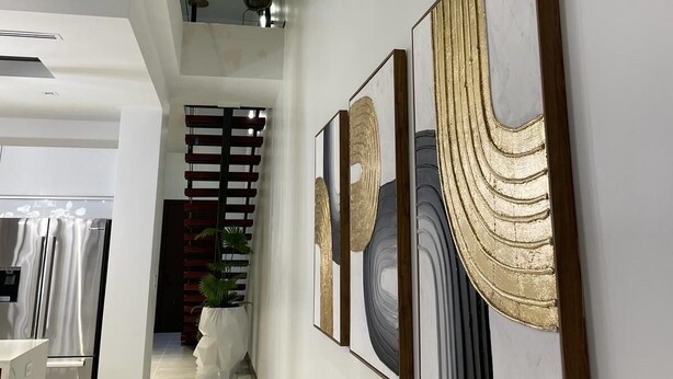 A modern interior with a hallway leading to a dining area, featuring artwork on the walls and a potted plant. -      Casa Vacacional para 10 
Alberca Privada  Cerca de la Playa (South Padre Island)