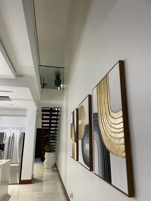 Ein modernes Interieur mit einer Diele, die in einen Essbereich führt, mit Kunstwerken an den Wänden und einer Topfpflanze.