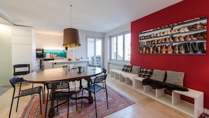 Un espacio habitable moderno con comedor, cocina y una pared para exhibir zapatos.