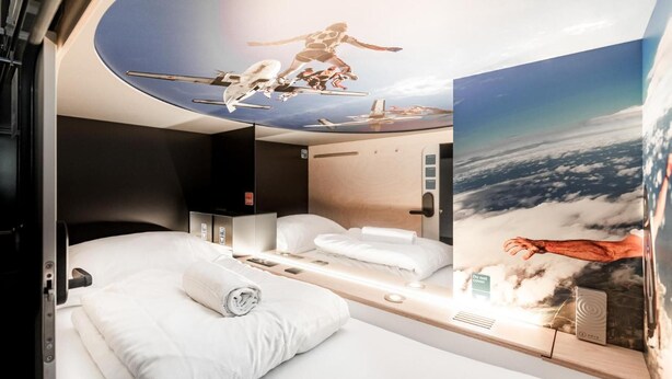 Una habitación de hotel moderna con una cama grande, un escritorio y vista al cielo.