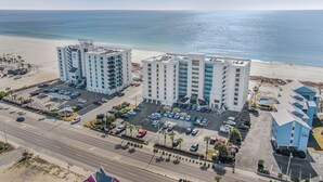 Ein Hotel direkt am Strand mit mehreren Etagen, Parkplätzen und Meerblick.
