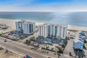Ein Hotel direkt am Strand mit mehreren Etagen, Parkplätzen und Meerblick.