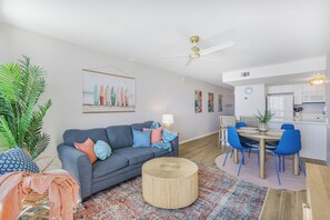 Ein modernes Wohnzimmer mit einer Couch, einem Couchtisch und einem Essbereich mit Stühlen.