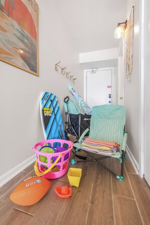 A room with a baby stroller, a baby bathtub, and a surfboard. - Beach Condo Loved for Location & Thoughtful Extras (Gulf Shores)