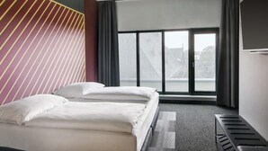 A hotel room with a bed, a large window, and a view of buildings. - B&B Hotel Zwickau (Zwickau)