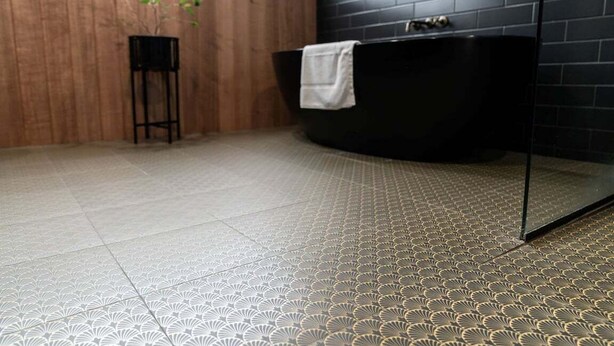 A bathroom with a black bathtub, a white towel, a potted plant, and a patterned floor. - White Pebble - Bicheno Accommodation (Bicheno)
