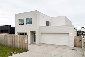 Ein modernes Wohnhaus mit zwei Etagen, einer Garage, einem Holzzaun und einem gepflegten Rasen.