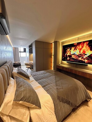 A modern bedroom with a large bed, a television mounted on the wall, and a seating area with a small table and chairs. - Luxury Loft Jacuzzi, Gym and Steam Bath Laureles (Medellín)