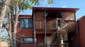 A two-story building with a wooden balcony, a spiral staircase, and a sign indicating a main pick-up/delivery service. - Charming Apartment in Downtown Lyons! 3bed/2bath (Lyons)