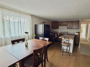 A compact kitchen with a refrigerator, a dining table, and a bar area. - Charming Apartment in Downtown Lyons! 3bed/2bath (Lyons)