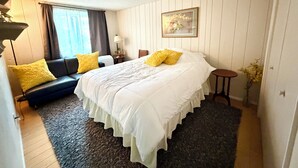 A hotel room with a bed, a sofa, a small table, and a window with curtains. - Charming Apartment in Downtown Lyons! 3bed/2bath (Lyons)