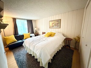Ein Hotelzimmer mit Bett, Sofa, kleinem Tisch und einem fenster mit Vorhängen.