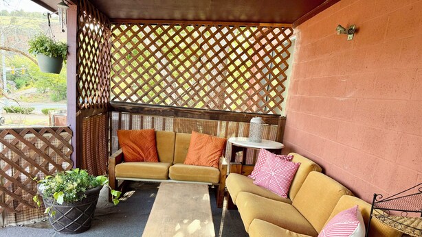 A covered outdoor seating area with a wooden bench, two sofas, and a small table with a lantern. - Charming Apartment in Downtown Lyons! 3bed/2bath (Lyons)