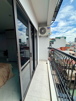 A balcony with a sliding glass door, a ceiling fan, and a view of the cityscape. -  Modern Balcony Studio 5 mins to Hanoi Station (Hà Nội)
