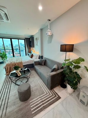 Una sala de estar moderna con sofá, mesa de centro y vistas de la ciudad a través de amplios ventanales.