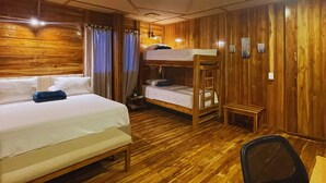 A room with wooden walls and floors, two bunk beds, a desk, and a chair.