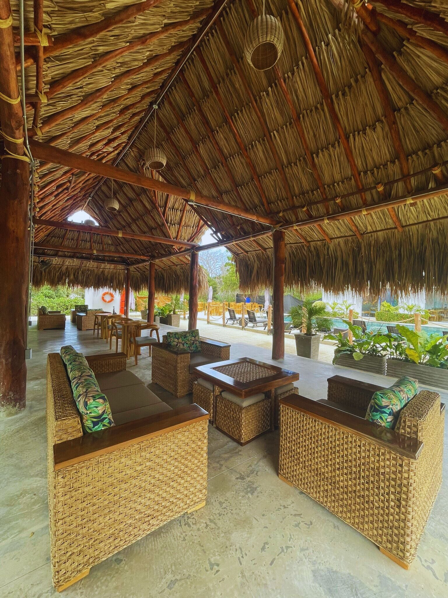A covered outdoor seating area with wicker furniture and a thatched roof.