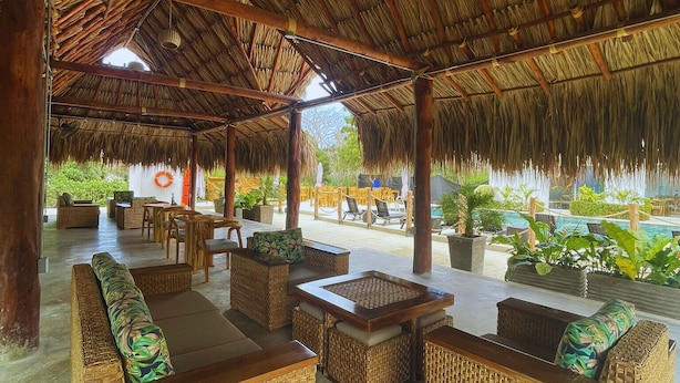 A covered outdoor seating area with wicker furniture and a thatched roof.