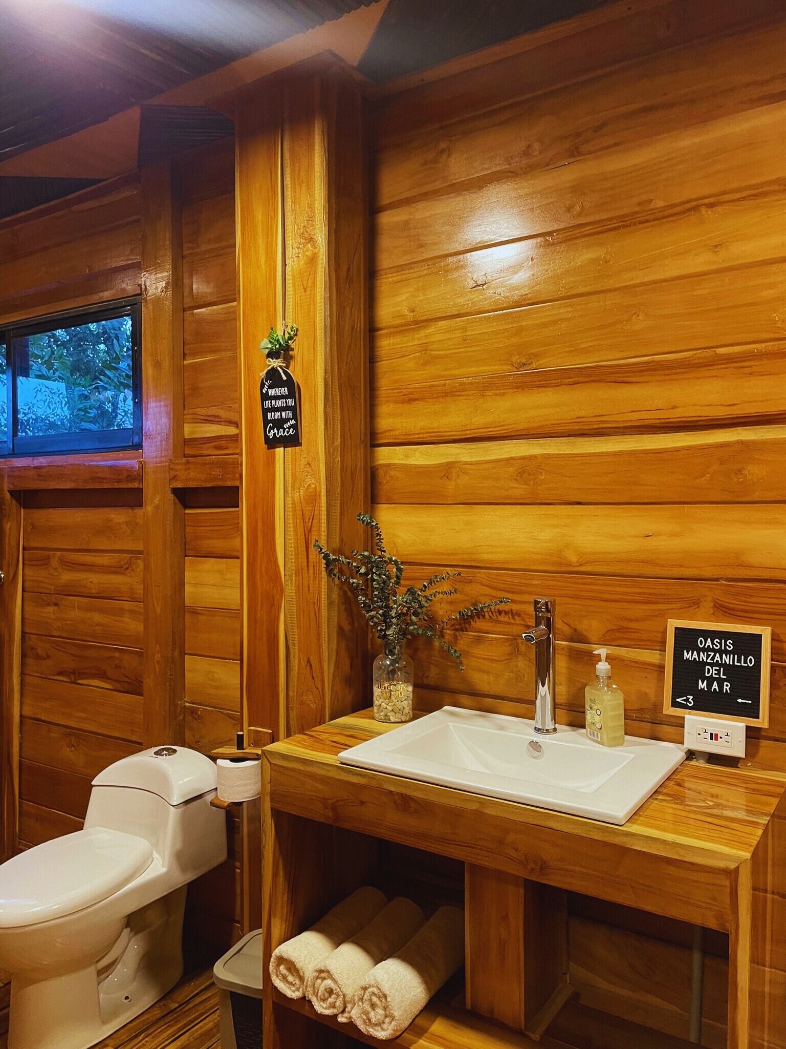 A wooden cabin bathroom with a toilet, sink, and towel rack.