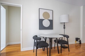A room with a round table, two chairs, a floor lamp, and a framed abstract artwork on the wall. - Blueground | Lenox Hill, view, nr Central Park (New York)