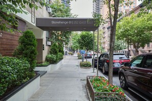 A street view with a sign for Stonehenge 61, a parking sign, and cars parked along the sidewalk. - Blueground | Lenox Hill, view, nr Central Park (New York)
