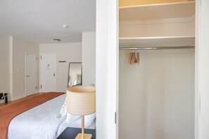 A hotel room with a bed, a bedside lamp, a wardrobe, and a mirror. - Blueground | Lenox Hill, view, nr Central Park (New York)
