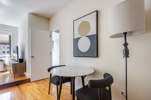 A modern dining area with a round table, two chairs, a floor lamp, and a wall-mounted abstract painting. - Blueground | Lenox Hill, view, nr Central Park (New York)