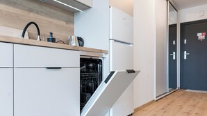 Eine moderne Küche mit weißen Schränken, einem Geschirrspüler und einem Kühlschrank.