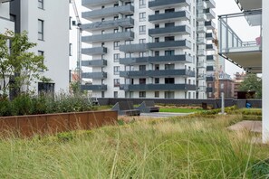 Ein mehrstöckiges Wohngebäude mit Balkonen, einem angelegten Gartenbereich und modernem architektonischen Stil.