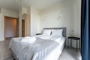 A modern bedroom with a large bed, bedside tables, and a wardrobe. - Bastion Wałowa Skyline Apartment #1 (Gdańsk)