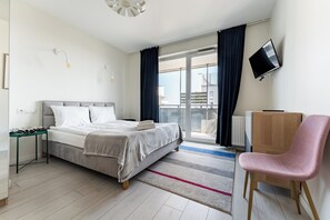 Et moderne hotelværelse med seng, skrivebord, stol, TV og udsigt ud
