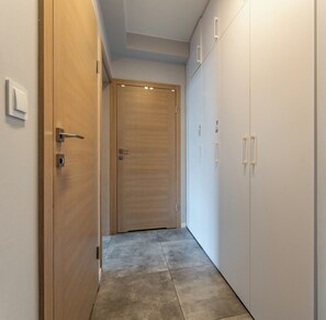A hallway with a wooden door, a white wardrobe, and a light switch on the wall.