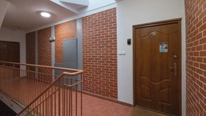 A corridor with a wooden door, a light switch, and a security intercom on the wall. - Targ Rybny Riverside Apartment (Szczecin)
