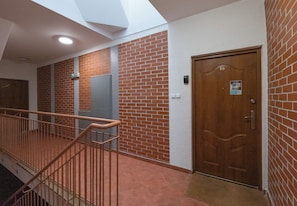 Ein Korridor mit einer Holztür, einem Lichtschalter und einem Gegensprechanlage an der Wand.