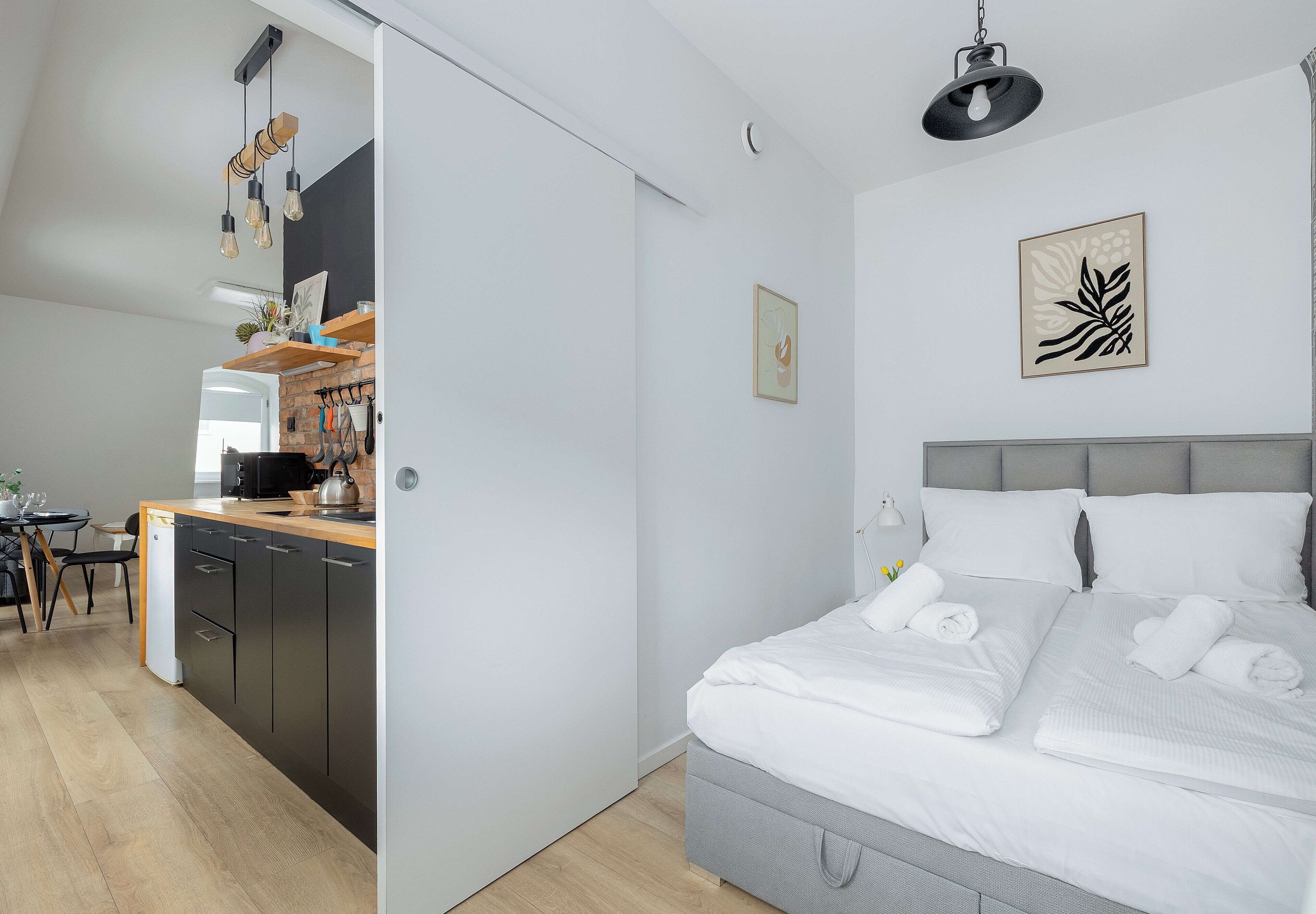 Ein modernes Schlafzimmer mit einem großen Bett, einer Küchenzeile mit Esstisch und einem Wohnbereich.