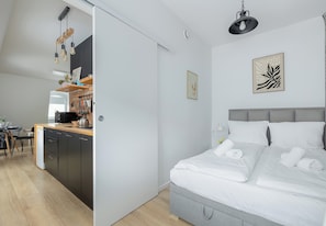 Ein modernes Schlafzimmer mit einem großen Bett, einer Küchenzeile mit Esstisch und einem Wohnbereich.