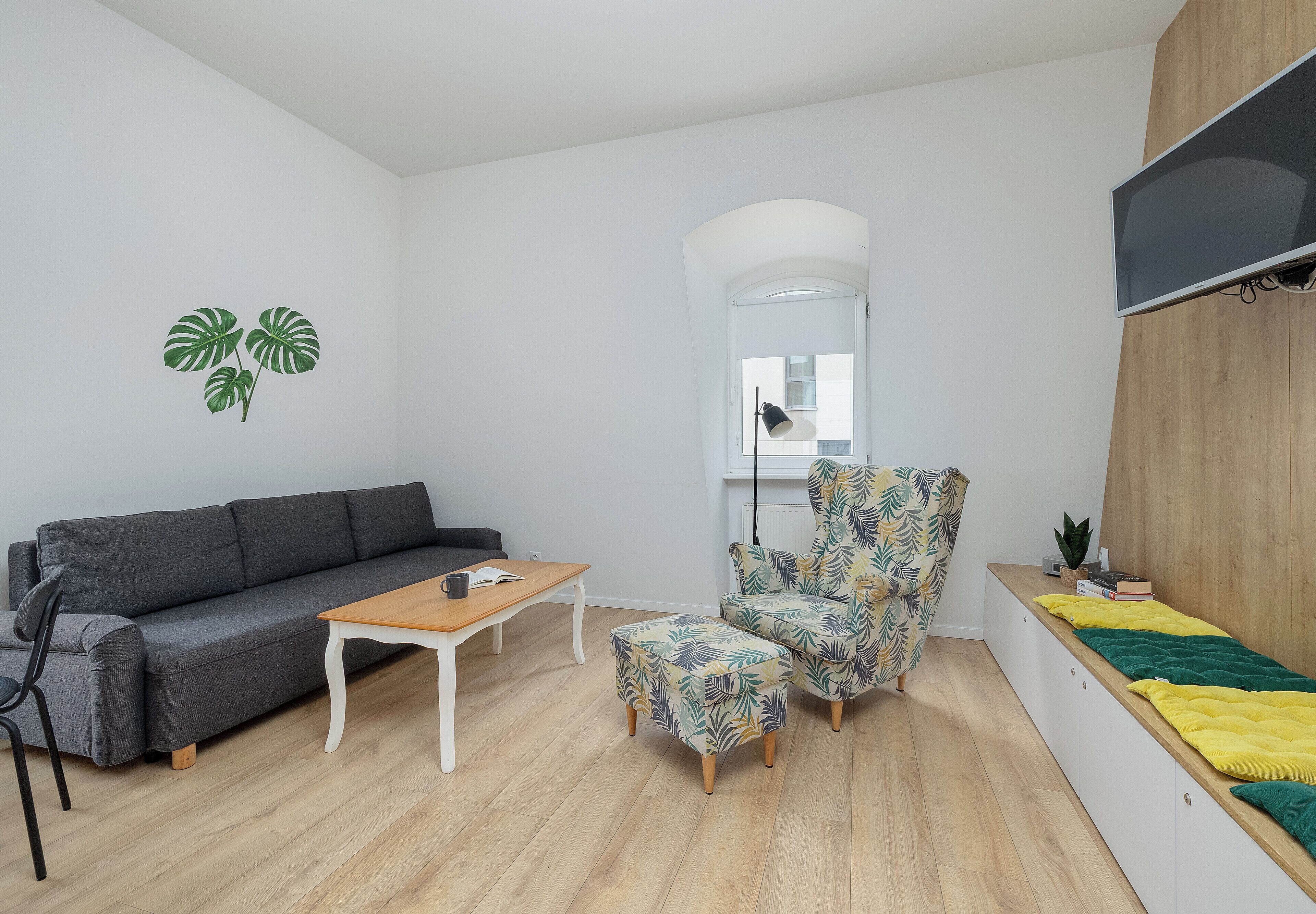 Ein stilvolles Wohnzimmer mit grauem Sofa, einem Holztisch, einem gemusterten Sessel und einem kleinen Beistelltisch.
