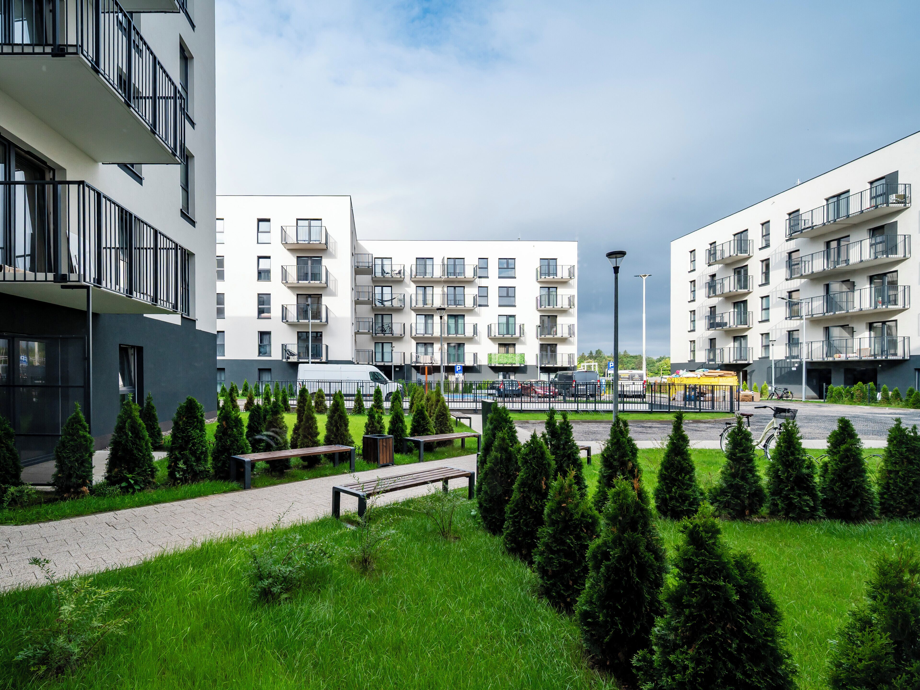 Um moderno complexo residencial com várias varandas, um caminho pavimentado e vegetação bem cuidada.