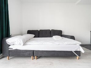 A modern bed with a grey frame, white bedding, and a dark grey headboard. - 1 Maja Prestige Studio (Łódź)
