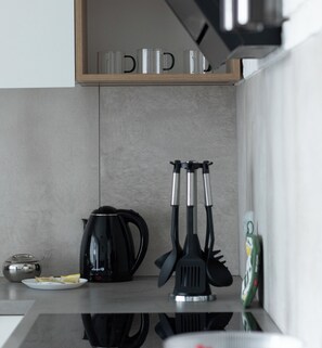 A kitchen counter with a coffee maker, spatulas, and a plate with packets. - Szczecin Bronowicka Malachite Studio (Szczecin)