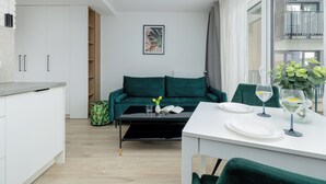 Moderni olohuone, jossa on ruokailutila, vihreä sohva ja näkymä ulos.